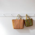 Two Fieldstone bags hanging on a rack against a white wall.